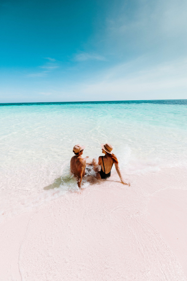 A couple sitting in the shallow water on a tropical beach